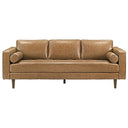 Front view of the Carly 88-inch tan genuine leather mid-century modern sofa against a white background, featuring three plush back cushions, a blind-tufted bench seat, two cylindrical bolster pillows, square track arms, and tapered dark wood legs.
