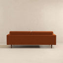 Back view of the Casey tufted back burnt-orange velvet upholstered sofa with tailored rear panel and tapered dark wood legs.