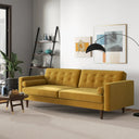 Casey tufted back gold velvet upholstered sofa with cylindrical bolster pillows and tapered wood legs, styled in a bright modern living room with wall art and an arched floor lamp.