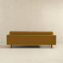 Back view of the Casey tufted back gold velvet upholstered sofa with tailored rear panel and tapered dark wood legs.