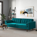 Casey tufted back teal velvet upholstered sofa with cylindrical bolster pillows and tapered wood legs, styled in a bright modern living room with wall art and an arched floor lamp.