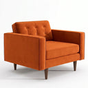 Casey mid-century modern armchair upholstered in burnt orange velvet with a button-tufted back cushion, track arms, and tapered dark wood legs.