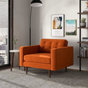 Casey burnt orange velvet armchair with button-tufted back and tapered wood legs in a modern living room setting