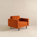 Casey mid-century modern armchair in burnt orange velvet upholstery with a button-tufted back cushion, square track arms, and tapered dark wood legs.