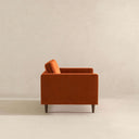 Side view of the Casey burnt orange velvet armchair featuring square track arms and tapered dark wood legs against a neutral background.