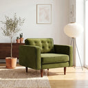 Casey olive green velvet armchair with button-tufted back and tapered wood legs in a sunlit modern living room.