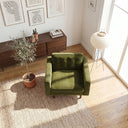 Top-down view of a Casey olive green velvet armchair with a tufted back cushion, styled on a textured woven rug in a sunlit modern living room beside a potted olive tree.