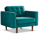 Casey teal velvet armchair featuring a button-tufted back cushion, piped edges, and tapered wood legs in a mid-century modern style.