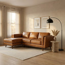 Chase 91-inch tan genuine leather left-facing sectional sofa with wooden legs styled in a sunlit living room with neutral decor, side table, and black arched floor lamp.