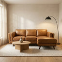 Chase 91-inch tan genuine leather right-facing sectional sofa styled in a minimalist living room with a round wooden coffee table, textured area rug, and black arched floor lamp.