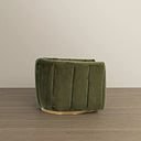 Side view of a modern olive green velvet barrel swivel chair featuring vertical channel tufting along its curved back and sides, resting on a round brushed brass plinth base against a neutral beige wall and light wood flooring.