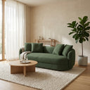 Dina 85-inch modern olive green boucle sofa with matching throw pillows, styled in a minimalist living room with a round wooden coffee table, cream woven rug, and a potted fiddle-leaf fig plant.