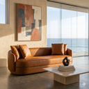 Modern living room with a cognac leather sofa, abstract painting, and ocean view.