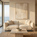 Elena 89 Mid-Century Modern cream boucle sofa with matching throw pillows in a minimalist living room featuring a travertine coffee table, woven rug, and floor-to-ceiling windows with an ocean view.