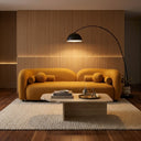 Modern Japandi living room featuring the Elissa 93-inch mustard yellow boucle sofa with a curved backrest and round cushions, positioned in front of a vertical wood slat accent wall with warm LED backlighting. An arched black floor lamp illuminates the scene, which includes a travertine stone coffee table on a cream woven rug.