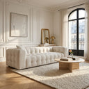 Elizia 86-inch modern Chesterfield cream boucle sofa with deep tufted channeling in a bright Parisian-style living room. The sofa is styled with a round travertine coffee table on a textured cream area rug, set against classic white paneled walls and a large arched black metal window.