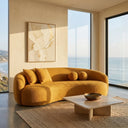 Enzo 89-inch Japandi gold boucle sofa with matching throw pillows in a modern minimalist living room featuring floor-to-ceiling windows with ocean views, a travertine coffee table, and abstract wall art.