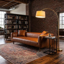 I will list the current permissions to see if I have access to the file.
I will try viewing the image file to read it.
Erling 86 cognac vegan eco-leather sofa in an industrial loft living room with an exposed brick wall, brass arc floor lamp, and patterned area rug.