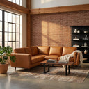 Eugina 92-inch tan genuine leather corner sectional sofa styled in an industrial loft living room with an exposed brick wall, rustic wood coffee table, patterned area rug, and large windows.