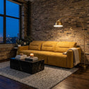 Modern industrial living room featuring the Franca 107 gold velvet power slider sofa set against an exposed brick wall, styled with a black marble coffee table, a textured gray area rug, and a curved brass arc floor lamp.