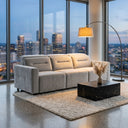 Franca 107 Light Grey Velvet Power Slider Sofa in a modern high-rise apartment living room with floor-to-ceiling windows displaying a city skyline view at dusk, featuring a black marble coffee table, textured rug, and arched floor lamp.