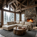 Cozy rustic cabin living room featuring the Gamila 110-inch beige genuine top-grain leather left-facing sectional sofa, styled with a knit throw blanket, a rustic tree stump coffee table, a textured gray area rug, a warm stone fireplace, and large windows showcasing a snowy winter forest.