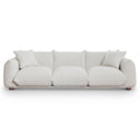 Kely 100 cream boucle upholstered three-seater sofa with plush cushions, matching throw pillows, and low wooden legs, isolated on a white background.