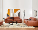 The Kennon leather sofa and loveseat styled in a modern living room with abstract art, a shaggy rug, and a contemporary floor lamp.