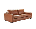 A three-quarter view of the Kennon leather sofa, highlighting its wide track arm, deep plush cushions, and the tailored topstitching on the caramel leather.