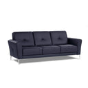 A three-quarter view of a dark blue contemporary modern leather sofa with buttonless tufting and chrome metal legs in a white back ground.