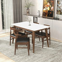 Mid-century modern rectangular dining table with a white top and dark walnut-toned wooden legs, surrounded by four matching wooden chairs with black cushioned seats on a gray area rug in a bright dining room.
