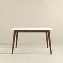 Front view of the Leroy 47-inch rectangular dining table featuring a smooth white beveled tabletop supported by a dark brown wood apron and four angled, tapered wooden legs against a textured beige wall and floor.
