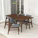 Mid-century modern rectangular dark walnut dining table surrounded by four matching wooden chairs with gray fabric seats and backs, set on a textured cream oval rug in a bright dining room with white cabinets and sheer curtains.
