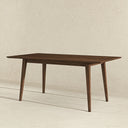 Mid-century modern 63-inch rectangular dining table in dark walnut wood, featuring a beveled tabletop and four angled, tapered legs, set against a neutral textured beige wall and light stone floor.
