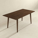 Three-quarter elevated view of the Leroy 63-inch rectangular dining table in dark walnut wood, featuring a slim beveled tabletop with natural wood grain and four slightly splayed, tapered legs against a neutral cream studio backdrop.
