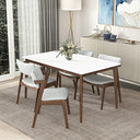 Lina 60-inch rectangular dining table featuring a smooth white tabletop and tapered brown wood legs, surrounded by four gray upholstered wooden chairs on a textured rug in a bright, modern dining room.
