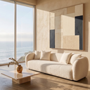Lina 84 Ivory Boucle Sofa in a modern, sunlit living room with a travertine stone coffee table, abstract wall art, and scenic coastal ocean views through large windows.