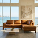 Luca 98-inch tan genuine leather right-facing sectional sofa with plush back cushions and dark wood legs in a sunlit modern living room overlooking the ocean.