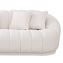 Close-up of the right side of a curved white French bouclé sofa featuring plush vertical channel tufting and two matching square throw pillows against a plain white background.
