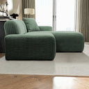 Green corduroy right-facing sectional sofa with chaise lounge and matching accent pillow on a cream textured rug in a modern living room.