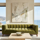 Mia 90-inch mid-century modern green velvet sofa featuring vertical channel tufting, set in a bright, modern living room with ocean views and a stone coffee table.