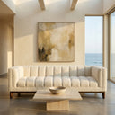 Mia 90-inch mid-century modern white boucle sofa with vertical channel tufting and dark wood legs, styled with a travertine stone coffee table in a bright minimalist living room with a large abstract painting and ocean views.