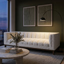 Mia 90-inch mid-century modern white boucle channeled sofa in a styled living room with olive green walls, a black arc floor lamp, and a travertine coffee table.
