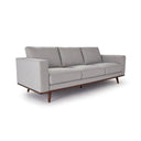 A three-quarter view of a gray upholstered Olwyn Sofa with a full wood base and wide track arms, presented against a white background.