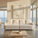 Modern minimalist living room featuring the Pina 115-inch cream bouclé sofa, positioned in front of a neutral abstract painting and large windows with scenic ocean views.