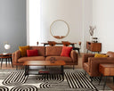 A brown, upholstered Rehan Sofa with a minimalist design, featuring a sleek backrest and seat with metallic accents.
