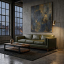 Modern Rita 91-inch olive green top-grain leather sofa in an industrial loft living room with concrete walls, a large abstract painting, a rustic wood coffee table, and a brass floor lamp.