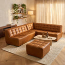 Selia 92-inch comfy chic sectional sofa with matching ottoman in cognac brown tufted leather, styled with a low travertine coffee table and textured cream rug in a sunlit living room.