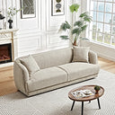 Stacey 87" cream luxury fabric sofa with curved silhouette and two matching throw pillows on a geometric rug in a bright, modern living room.

