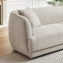 Close-up view of the Stacey cream luxury fabric sofa featuring a curved armrest, textured upholstery, and a matching throw pillow on a geometric patterned rug.
